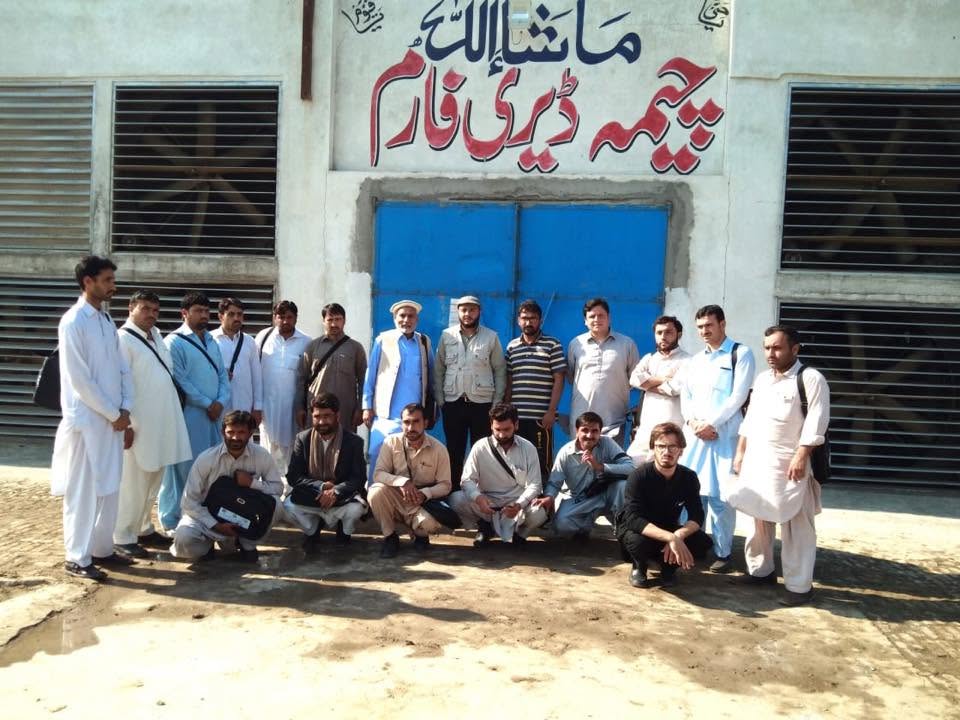Group of staff and visitors at the Cheema Dairy Farm entrance under the Urdu signboard